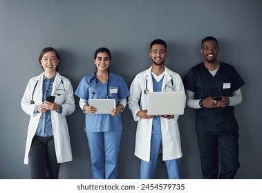 Doctor, teamwork and technology on wall background for research, planning and multimedia workflow. Healthcare worker, group and nurse in portrait with laptop, tablet and phone for contact or about us - Powered by Shutterstock