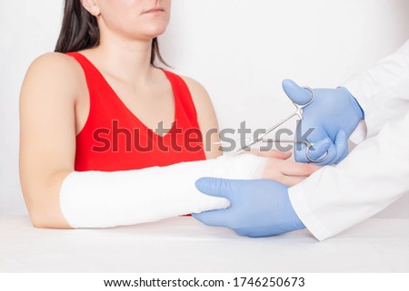 Doctor traumatologist removes the fixing bandage for a girl who has a tear and sprain on her arm, medical, ligament rupture