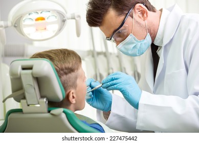 The doctor treats a tooth of little boy at dentist's clinic.