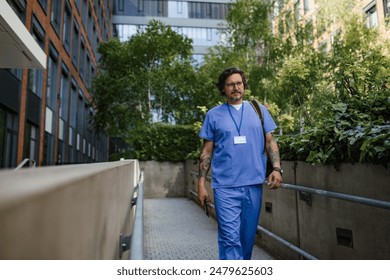 Doctor in uniform going home from work, walking in front of hospital building. Work-life balance of healthcare worker. - Powered by Shutterstock