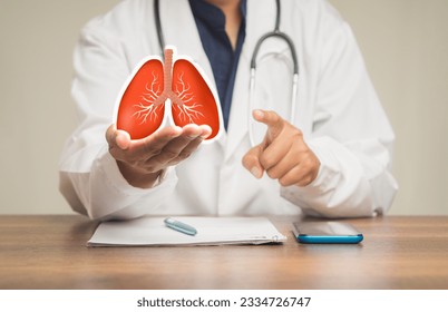 A doctor in a uniform holding a lung shape symbol while sitting at a table in the hospital. World tuberculosis day, world no tobacco day, lung cancer, pulmonary hypertension, pneumonia.