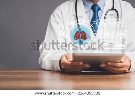A doctor in a uniform read a report lung checkup on a virtual screen while sitting at the table in the hospital. World no tobacco day, lung cancer, pulmonary hypertension, pneumonia