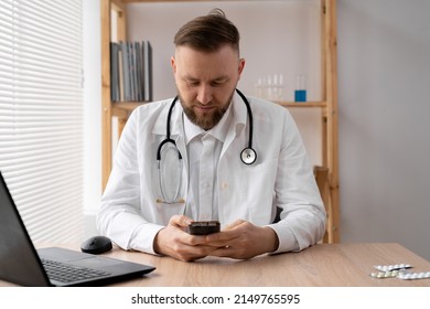 The Doctor Uses A Mobile Smartphone, Works On A Laptop In A Medical Office In A Hospital, EHR Electronic Medical Record System, Cloud Storage Technology Concept.