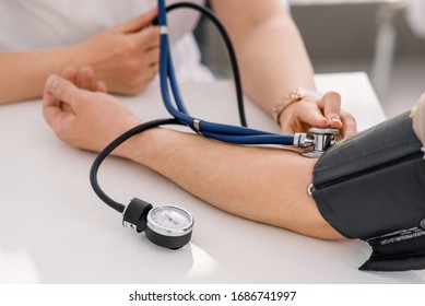 The Doctor Uses A Sphygmomanometer With A Stethoscope To Check The Patient's Blood Pressure In The Hospital.