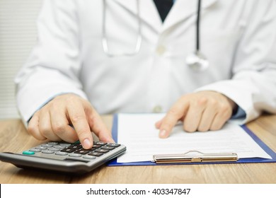 Doctor is using calculator to sum all of expenses