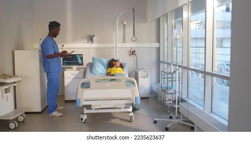 Doctor using digital notepad visiting African-American child patient. Sick little African-American girl lying in hospital bed with nurse using digital tablet during checkup in hospital ward - Powered by Shutterstock