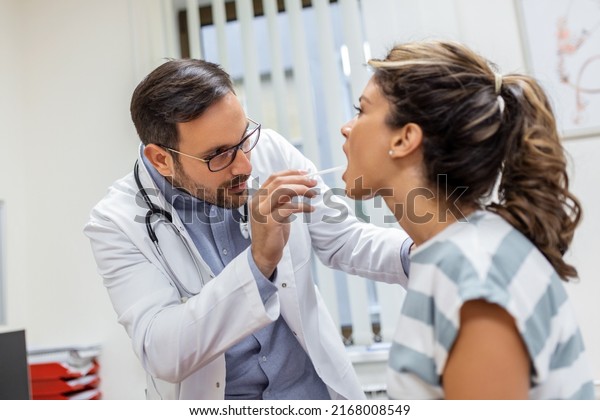 Doctor using inspection spatula to examine\
patient throat. ENT doctor doing throat exam of a woman. patient\
opened her mouth to throat\
check-up