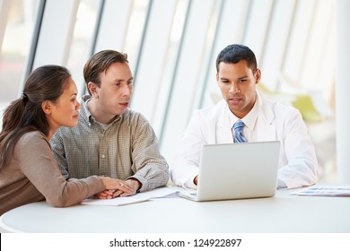 Doctor Using Laptop Discussing Treatment With Patients