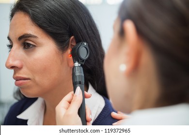Doctor using otoscope instrument to check womans ear in hospital, Healthcare workers in the Coronavirus Covid19 pandemic