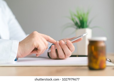 Doctor Using Smartphone App In Hospital Office, Close Up Of Female Person Hands Holding Mobile Phone. Modern Technology In Health Care And Medicine.