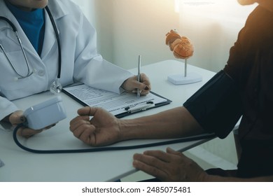 Doctor using sphygmomanometer with stethoscope checking blood pressure to a patient in the hospital.