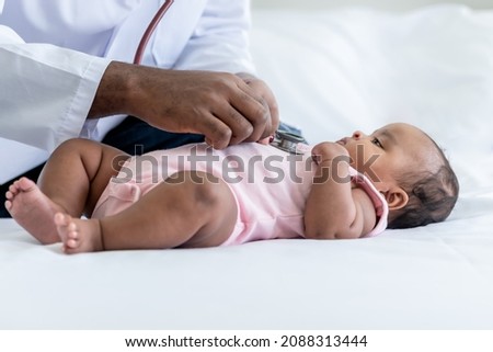 The doctor is using a stethoscope, checking the respiratory system and heartbeat Of a 3-month-old baby newborn, who is half African half Thai, to Infant health care and treatment concept.