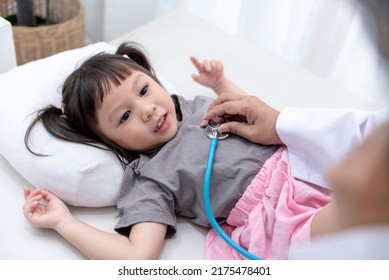 The Doctor Is Using A Stethoscope Listen To Heart Rate Of A 3 Year Old  Girl Patient Which Lying On The Patient's Bed,  To Health Care And Children Concept.