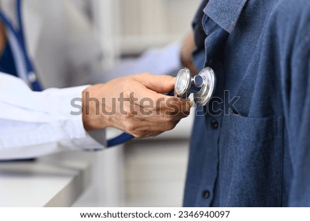Doctor using stethoscope, listening to male patient breath or heartbeat. Healthy care, medicine and insurance concept.