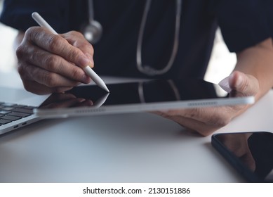 Doctor using stylus pen on digital tablet and working on laptop computer at doctor office. Surgeon recording operation result on digital tablet, electronic medical record system concept - Powered by Shutterstock