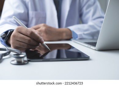 Doctor Using Stylus Pen On Digital Tablet, Filling Medical Checklist And Prescription On Digital Document With Laptop Computer On Table In Medical Office  In Hospital, Close Up