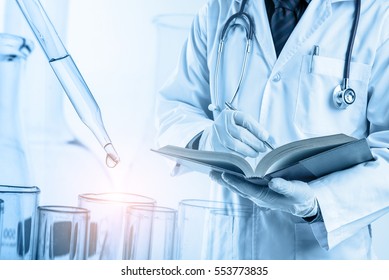 Doctor Using Text Book With Laboratory, Medical And Science Research Concept 