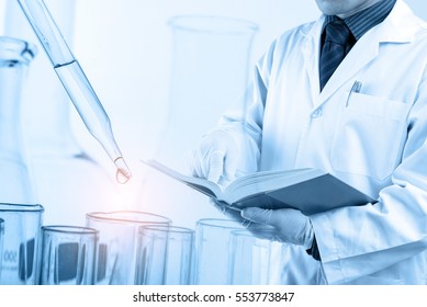 Doctor Using Text Book With Laboratory, Medical And Science Research Concept 