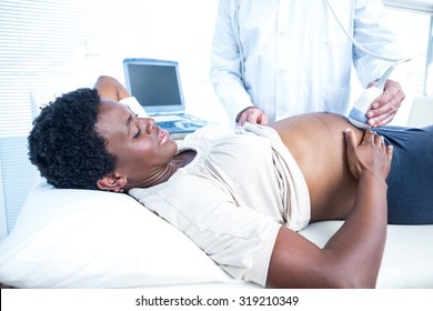 Doctor using ultrasound machine on pregnant woman in clinic