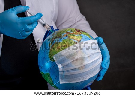 Doctor vaccinating the earth because of coronavirus with blue medical gloves