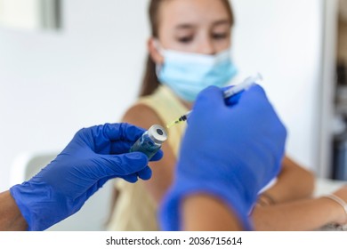 Doctor vaccinating girl. Injecting COVID-19 vaccine into patient's arm. Young child with face mask getting vaccinated, coronavirus, covid-19 and vaccination concept. - Shutterstock ID 2036715614