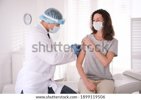 Doctor vaccinating mature woman against Covid-19 in clinic
