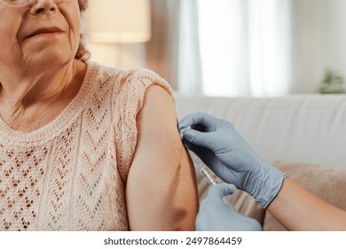 Doctor vaccinating a senior woman at home, ensuring her well-being and safety. Vaccination, elderly, healthcare concept - Powered by Shutterstock