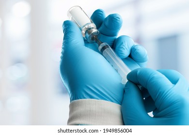 A doctor vaccinator holds a dose of a COVID-19 vaccine. - Shutterstock ID 1949856004