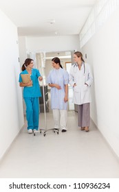 Doctor Walking With A Patient And A Nurse In A Hallway, Healthcare Workers In The Coronavirus Covid19 Pandemic