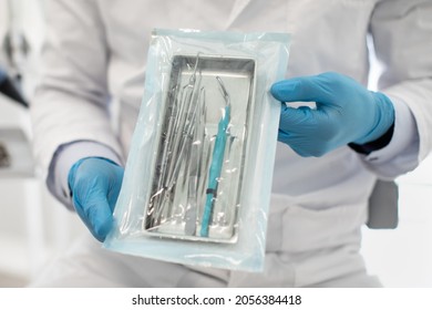 Doctor Wearing Blue Sterile Gloves Demonstating Sealed Sterilization Pouch With Clean Dental Tools, Unrecognizable Male Dentist Showing Stomatological Instruments, Ready For Teeth Treatment, Closeup - Shutterstock ID 2056384418