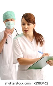 Doctor wearing cap and mask dictating notes to the nurse