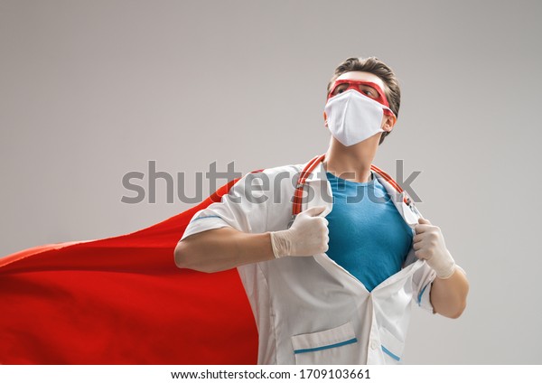 Doctor wearing facemask and\
superhero cape during coronavirus outbreak. Virus and illness\
protection, quarantine. COVID-2019. Super hero power for \
medicine.