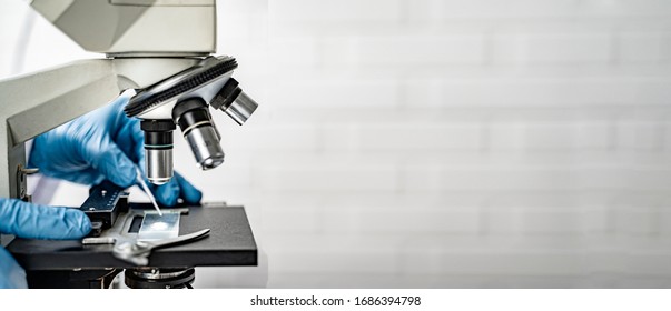 Doctor Wearing Protective Gloves Using Microscope Researching Corona Virus Microscopic Cells Testing Vaccination Cure, Medical Center Lab China Wuhan World Health Organization Research Facilities