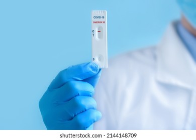A doctor wearing a protective mask and gloves shows a rapid laboratory test for COVID-19 Omicron ?? variant strain to detect IgM and IgG antibodies to the new coronavirus. Negative result.