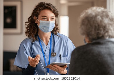 Arzt mit Schutzmaske, der ältere Patienten während des Hausbesuchs während der Covid-19-Pandemie unterstützt und aufmuntert. Krankenschwester und alte Frau, die während des Ausbruchs von Koronavirus und Grippe Fieber tragen. 