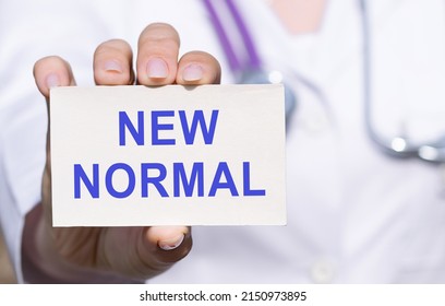 Doctor In White Clothes Showing A White Card With Text NEW NORMAL Covid 19 And Coronavirus Concept