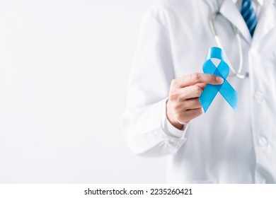 doctor in a white coat hands holding Blue ribbon for supporting people living and illness, Colon cancer, Colorectal cancer, Child Abuse awareness, world diabetes day, International Men's Day