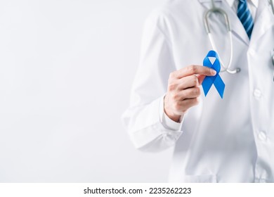 doctor in a white coat hands holding Blue ribbon for supporting people living and illness, Colon cancer, Colorectal cancer, Child Abuse awareness, world diabetes day, International Men's Day - Powered by Shutterstock