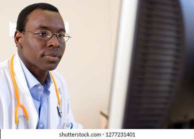 Doctor in white coat with stethoscope working on computer in hospital: stockfoto