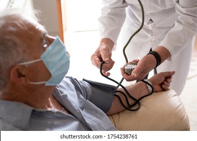 Doctor In A White Coat Takes Pressure To An Elderly Patient With A Mask