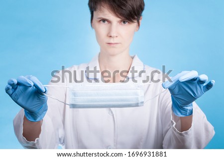 doctor in a white medical coat and blue gloves shows a medical mask. concept of protection from the virus in pandemic