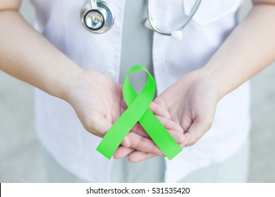 Doctor In White Uniform Hold Lime Green Ribbon Awareness In Hand For Kabuki Syndrome,Lyme Disease,Lymphoma,Muscular Dystrophy,Non-Hodgkin's Lymphoma,Sandhoff Disease,Spinal Cord Injuries (SCI), Mental