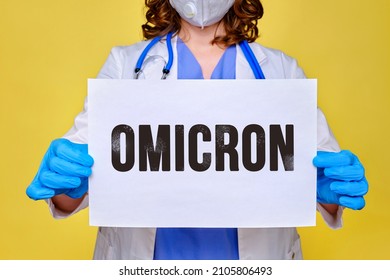 A Doctor In A White Uniform Holds A Sheet Of Paper With The Text Of The New Variant Covid Virus Omicron, Yellow Background