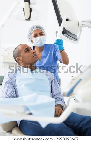 Doctor woman dentist shows patient an x-ray