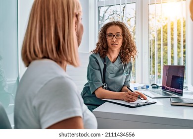 Doctor woman dressed in medical suit talking in office. Reception and consultation with a doctor. - Shutterstock ID 2111434556