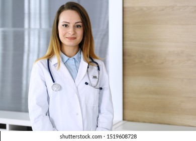 Doctor Woman Headshot While Standing In Hospital Office. Physician At Workplace, Portrait Photo. Medicine And Health Care Concept