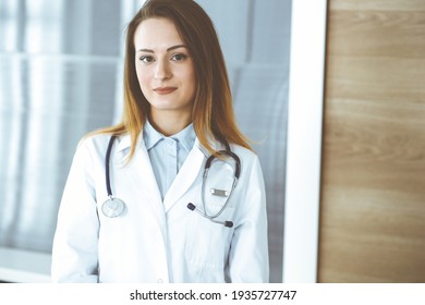 Doctor Woman Headshot While Standing In Hospital Office. Physician At Workplace, Portrait Photo. Medicine And Health Care Concept