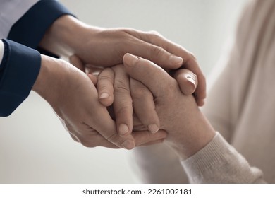 Doctor woman holding hands of senior female patient, touching folded palms with came, support, compassion, giving comfort, medical advice. Close up cropped shot - Powered by Shutterstock