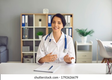 Doctor Woman Looking At The Computer Web Camera Smiling At The Patient Sitting At The Table In The Office Of The Clinic.