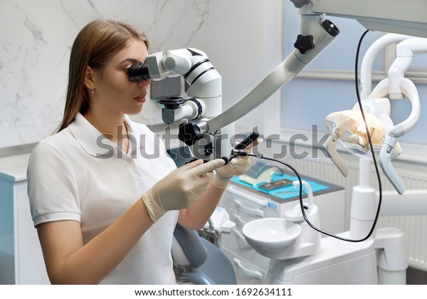 Doctor woman with\
microscope, young girl medic studies on a microscope, dentistry,\
virus, laboratory